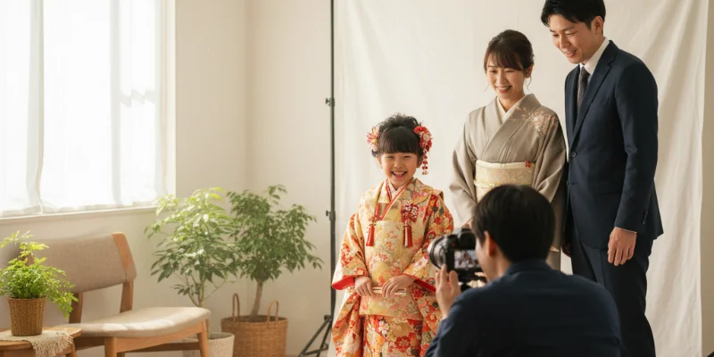 自然光が差し込む明るい室内で、子供が笑顔で撮影を受けている様子。着物姿の子供と、優しく見守る親の姿が写っている。